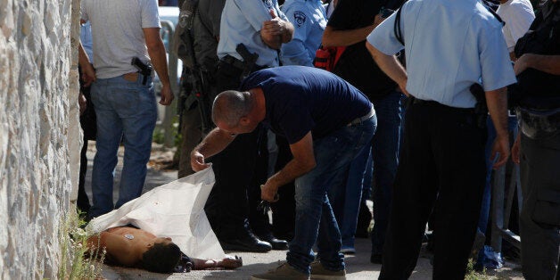 Israeli police stand around the body of a Palestinian in Jerusalem Saturday, Oct. 17, 2015. Police spokeswoman Luba Samri said a 16-year-old Palestinian drew a knife on officers when they approached him in Jerusalem and asked for identification Saturday. She said the officers opened fire and killed him. (AP Photo/Mahmoud Illean)