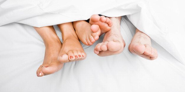 Close-up of a couple' || chr(39) || 's feet with their child on the bed