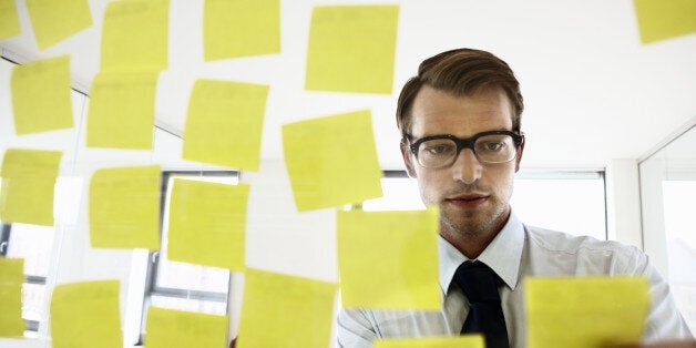 employee fixing sticky notes on a glass screen