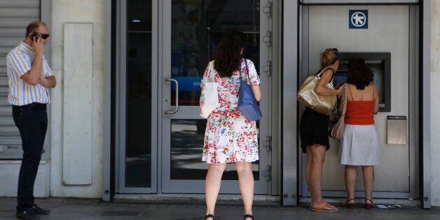 The women right use the ATM machine as two other people wait outside of a closed bank in central Athens, Wednesday, July 8, 2015. Frustrated and angry eurozone leaders fearing for the future of their common currency gave the Greek Prime Minister Alexis Tsipras a last-minute chance Tuesday to finally come up with a viable proposal on how to save his country from financial ruin. (AP Photo/Petros Karadjias)