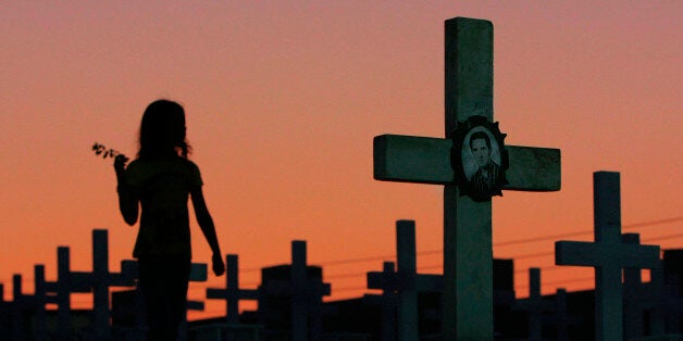 ** FILE ** In this Friday, July 18, 2008, file photo, an unidentified girl passes by the graves of Greek and Cypriot soldiers who were killed in the 1974 Turkish invasion of Cyprus at the Tymvos Macedonitissas military cemetery in the divided capital of Nicosia. Cyprus urged Turkey on Friday, Jan. 23, 2009 to account for some 1,500 people missing since its invasion of the island 35 years ago, after a former Turkish army conscript described how he had executed a prisoner of war. Actor Attila Olgac reportedly told a Turkish television program this week that while serving in the Turkish army during the 1974 invasion he shot at least one prisoner dead on orders from a superior.