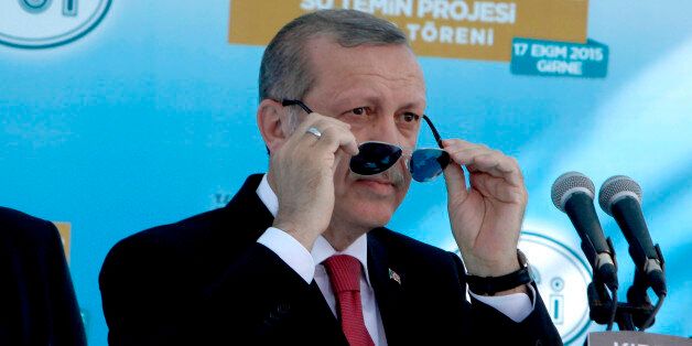 Turkish President Recep Tayyip Erdogan adjust his sunglasses before making a speech to his supporters, during an inauguration for an undersea pipeline to carry fresh water from Turkey to the breakaway Turkish Cypriot north of ethnically split Cyprus in Mirtou village, Saturday, Oct. 17, 2015. Erdogan and other Turkish officials symbolically turned open a large valve, starting the flow of water through the 107-kilometer (66.5-mile) pipeline at a ceremony at the Mediterranean town of Anamur, before leaving for Cyprus for a second ceremony in Cyprus marking the water's arrival. (AP Photo/Petros Karadjias)
