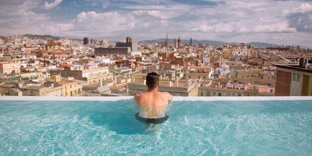 Picture of the young guy taken from the back overlooking Barcelona, taken in the pool on the top floor of the luxury hotel.