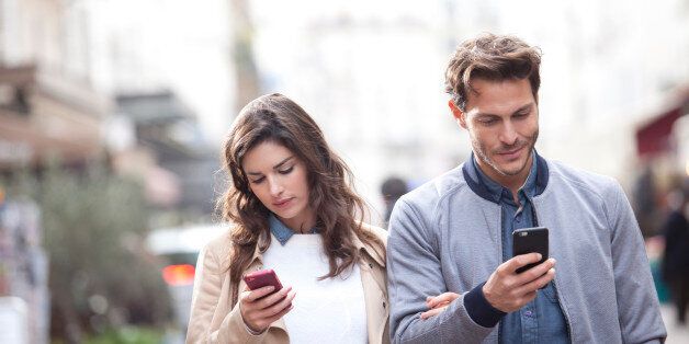 Couple walking in the street watching their phones