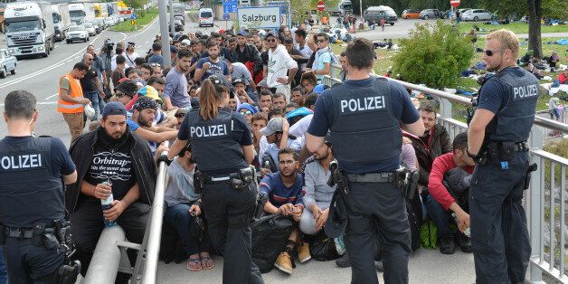 Refugees sit on a bridge after police stopped them at the border between Austria and Germany in Salzburg, Austria, Thursday, Sept. 17, 2015. (AP Photo/Kerstin Joensson)