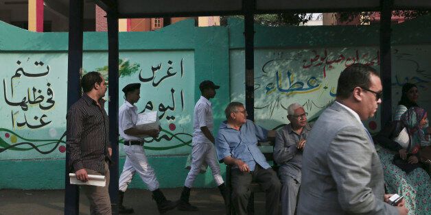 Egyptian officials and police arrive with voting cards at the entrance of a polling center, before polls open, during the first round of the parliamentary election in Cairo, Egypt, Sunday, Oct. 18, 2015. (AP Photo/Nariman El-Mofty)