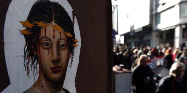 Wall art is pictured next to demonstrators during a 24-hour strike against the austerity measures in Athens on January 17, 2012. Greece's main union called for a strike in Athens as the government upped pressure on labour unions to accept wage cuts to avert bankruptcy. The GSEE union said strike would send a 'strong message' to the government, employers and Greece's institutional creditors 'who are planning new and harsher anti-labour measures.' AFP PHOTO / ARIS MESSINIS (Photo credit should rea