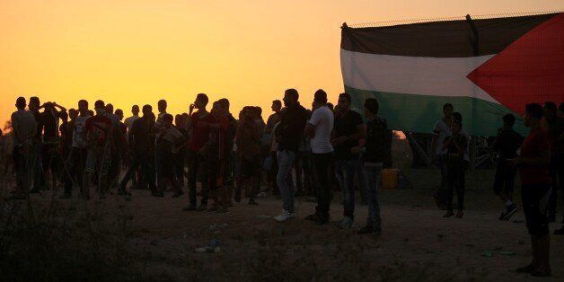 DEIR AL-BALAH, GAZA - OCTOBER 15: Palestinian protesters attach Palestinian flag to the barbed wires on the Gaza border during a protest near Al- Bureij refugee camp, Gaza on October 15, 2015. (Photo by Ashraf Amra/Anadolu Agency/Getty Images)