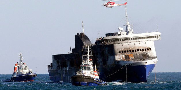 The Norman Atlantic ferry is being towed into the port of Brindisi, Italy, Friday, Jan. 2, 2015. The blaze that broke out Sunday and torched the ferry has killed at least 11 people and authorities prepared to search it for possible more dead. Italy says 477 people were rescued, most by helicopters that plucked survivors off the top deck in gale-force winds and carried them to nearby boats. (AP Photo/Antonio Calanni)
