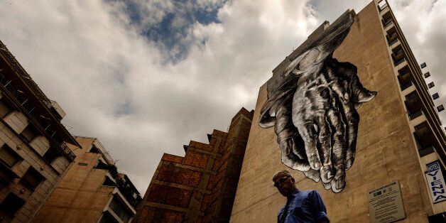 A man walks down a street with a turned upside down mural inspired on