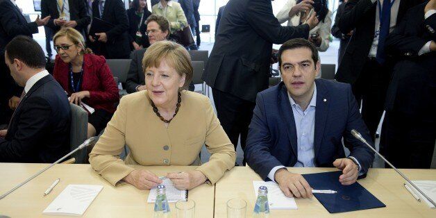 German chancellor Angela Merkel (L) talks with Greek prime minister Alexis Tsipras at the begining of the second day of the fourth European Union (EU) eastern Partnership Summit in Riga, on May 22, 2015 as Latvia holds the rotating presidency of the EU Council. EU leaders and their counterparts from Ukraine and five ex-Soviet states hold a summit focused on bolstering their ties, an initiative that has been undermined by Russia's intervention in Ukraine. AFP PHOTO / ALAIN JOCARD (Photo c