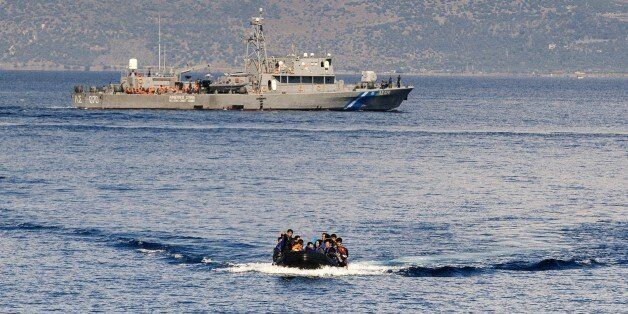 A Greek coast guard ship is seen behind a rubber boat with refugees and migrants near the Greek island of Lesbos after crossing the Aegean Sea from Turkey on October 13, 2015. Greece pledged On October 10, 2015 during talks with its EU partners to open its first so-called hotspot reception centre on the island of Lesbos within 10 days under EU efforts to better deal with the massive influx of migrants. AFP PHOTO / DIMITAR DILKOFF (Photo credit should read DIMITAR DILKOFF/AFP/Getty Images)