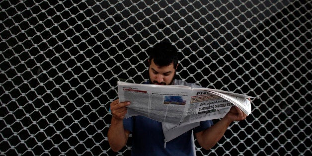 A demonstrator reads a newspaper outside the Greek finance ministry during a protest by the Communist affiliated trade union PAME in Athens, Greece, on Thursday, June 11, 2015. European Union President Donald Tusk accused Greece of playing games with its future in the euro zone and pressed Prime Minister Alexis Tsipras's government to make concessions in order to escape economic ruin. Photographer: Kostas Tsironis/Bloomberg via Getty Images