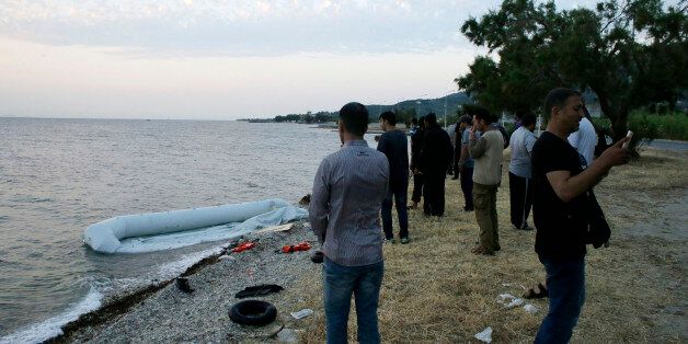 Syrian migrants gather next to their destroyed dinghy after their arrival from Turkish coasts at a Mytilene beach, on the northeastern Greek island of Lesvos, early Thursday, June 18, 2015. Around 100,000 migrants have entered Europe so far this year, with some 2,000 dead or missing during their perilous quest to reach the continent. Italy and Greece have borne the brunt of the surge, with many more migrants expected to arrive from June through to September. (AP Photo/Thanassis Stavrakis)