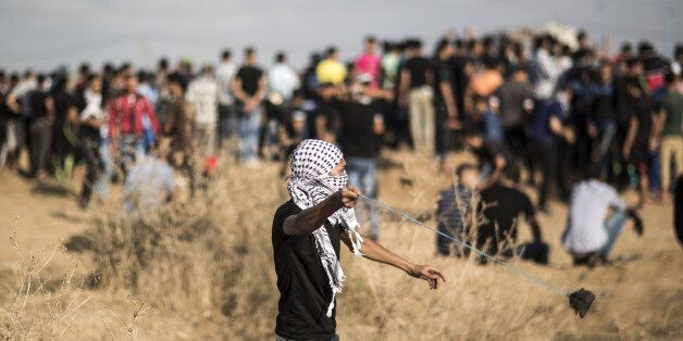 GAZA STRIP, Oct. 9, 2015-- A Palestinian protester hurls stones at Israeli troops during clashes near the Israeli border fence in Gaza City on Oct. 9, 2015. Seven Palestinians including a woman were killed in Israel and more than 45 injured in fierce clashes that broke out on Friday in both the West Bank and the Gaza Strip between Israeli soldiers and Palestinians, local medics and officials said. (Xinhua/Wissam Nassar via Getty Images)