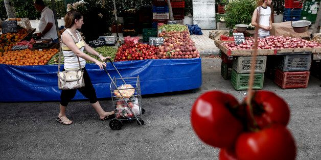 A customer pushes her shopping cart between food stalls at an open air street market in Athens, Greece, on Saturday, July 11, 2015. Both Prime Minister Alexis Tsipras and Greece's creditors face tough decisions about how to shore up the country's financial system and reopen its lenders, which have been shut for two weeks amid record deposit withdrawals and doubts over the country's place in the euro area. Photographer: Yorgos Karahalis/Bloomberg via Getty Images