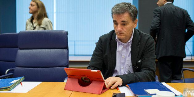 Euclid Tsakalotos, Greece's finance minister, looks at Apple Inc. iPad tablet device ahead of roundtable talks during a Eurogroup meeting in Luxembourg, on Monday, Oct. 5, 2015. French Finance Minister Michel Sapin said Greece needs to make good on its promises with euro-area lenders as soon as possible so the creditors can move on to discuss easing the country's debt burden. Photographer: Jasper Juinen/Bloomberg via Getty Images