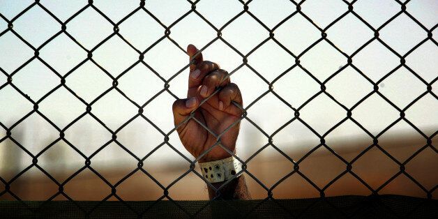 An Iraqi detainee holds onto a fence enclosing him at the Camp Cropper detention centre, located in Baghdad, on May 21, 2008. There are approximately 22,000 detainees being held by US forces in two detention facilities in Iraq, up from only about 14,000 before the American troop surge this year. Camp Cropper currently holds approximately 3,000 detainees. The detainee population contains, juveniles, insurgents of all anti-coalition groups in Iraq, and innocent Iraqis detained during military operations. Military officials have initiated programs for the detainees in the detention facility including educational classes, Islamic discussion courses, work programs, art classes and a vigorous review board to discuss with detainees the circumstances surrounding their arrest. AFP PHOTO/DAVID FURST (Photo credit should read DAVID FURST/AFP/Getty Images)
