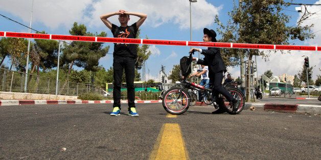 Israelis look at the scene of a stabbing attack in Jerusalem, Thursday, Oct. 8, 2015. A Palestinian stabbed a Jewish seminary student in Jerusalem on Thursday as the Israeli prime minister barred all Cabinet ministers and lawmakers from visiting a sensitive holy site in the Old City in an effort to calm tensions that have gripped the country for weeks. (AP Photo/Sebastian Scheiner)