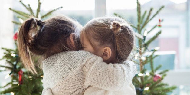 Girls hugging in front of Christmas trees