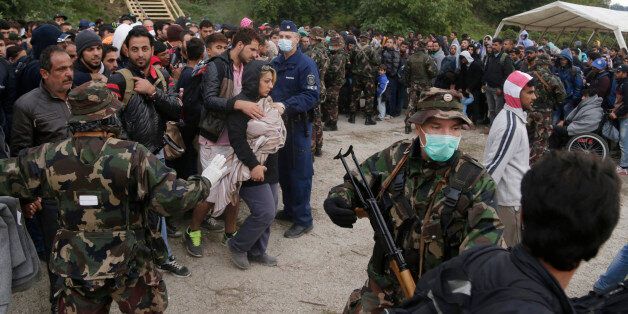 Hungarian soldiers attempt to organize a group of people that crossed the border with Croatia and arrived in Barcs, Hungary, Thursday, Sept. 24, 2015. Deeply divided European Union leaders have been called to an emergency summit to seek long-term responses to the continent's ballooning crisis of refugees and migrants, a historic challenge EU President Donald Tusk said the bloc has failed dismally to meet. (AP Photo/Petr David Josek)
