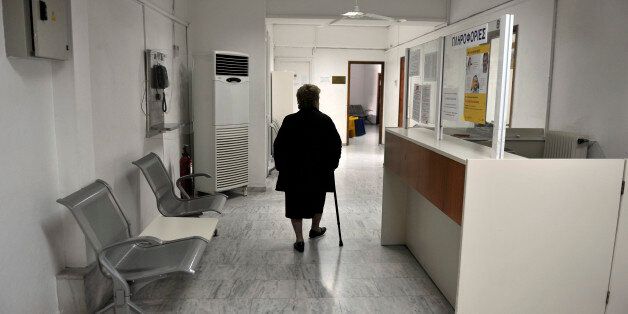 A woman walks a closed branch Greek state health fund EOPYY in an Athens suburb on February 17, 2014, as doctors and other staff refuse to hand over control of the organizations polyclinics despite the demands of the Health Ministry. Doctors at the state health fund EOPYY have been on strike since November, protesting against a planned restructuring of the loss-making organisation. The ministry insists the polyclinics will reopen in 30 days with a new system. AFP PHOTO/ LOUISA GOULIAMAKI (Photo credit should read LOUISA GOULIAMAKI/AFP/Getty Images)