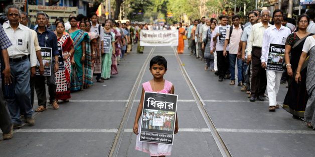A girl walks with others in a silent procession protesting the gang rape of a nun at a convent at Ranaghat, in Kolkata, India, Saturday, March 21, 2015. A nun in her 70s was gang-raped by a group of bandits when she tried to prevent them from committing a robbery in the Convent of Jesus and Mary School in West Bengal state's Nadia district, according to police. Poster reads âshame.â (AP Photo/ Bikas Das)