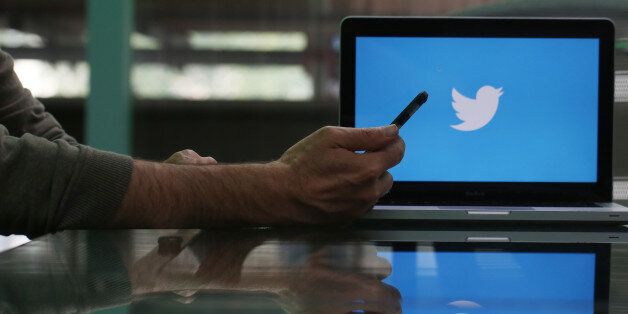 An Apple Inc. iPhone 6 smartphone is held as a laptop screen shows the Twitter Inc. logo in this arranged photograph taken in London, U.K., on Friday, May, 15, 2015. Facebook Inc. reached a deal with New York Times Co. and eight other media outlets to post stories directly to the social network's mobile news feeds, as publishers strive for new ways to expand their reach. Photographer: Chris Ratcliffe/Bloomberg via Getty Images