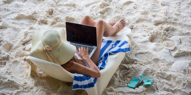 LA PASSE, LA DIGUE, SEYCHELLES - OCTOBER 03, 2015: Beautiful woman in a white bikini working with a laptop at Patata beach on October 03, 2015 in La Passe, La Digue, Seychelles. (Photo by EyesWideOpen/Getty Images)