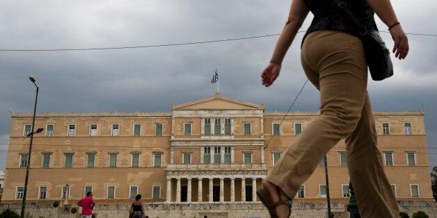 People walk past the Greek parliament in Athens, on Friday, Aug. 21, 2015. Greece's president asked the main opposition party Friday to try to form a new government, a day after Prime Minister Alexis Tsipras resigned and called an early election next month to deal with a governing party rebellion over Greece's third bailout deal.(AP Photo/Petros Giannakouris)