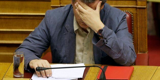 Greece's Finance Minister Euclid Tsakalotos reads his notes during a parliament meeting in Athens, Wednesday, July 15, 2015. Greece's prime minister was fighting to keep his government intact in the face of outrage over an austerity bill that parliament must pass Wednesday night if the country is to start negotiations on a new bailout and avoid financial collapse. (AP Photo/Thanassis Stavrakis)
