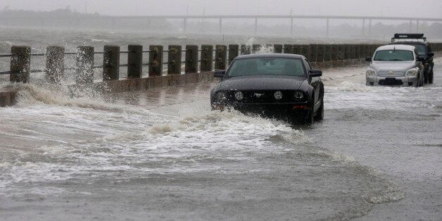 Waves break over a wall around cars parked on Bay Street in Charleston, S.C., Saturday, Oct. 3, 2015. A flash flood warning was in effect in parts of South Carolina, where authorities shut down the Charleston peninsula to motorists. (AP Photo/Chuck Burton)