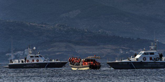 A boat carrying refugees and migrants stops between two Hellenic coast guard boats near the Greek island of Lesbos on September 30, 2015. Europe's migrant crisis was set to be in focus at the UN with Secretary General Ban Ki-moon seeking to muster a global response to the exodus of vast numbers of people from Syria and elsewhere. AFP PHOTO / ARIS MESSINIS (Photo credit should read ARIS MESSINIS/AFP/Getty Images)