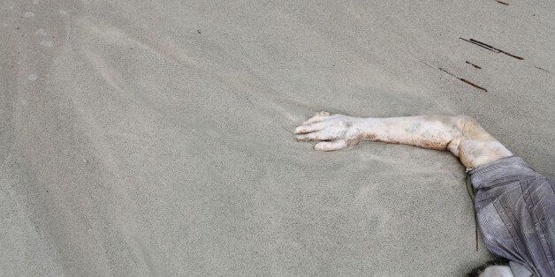 In this Monday, Sept. 7, 2015 photo, the body of a drowned man lies on the beach west of the town of Zuwara, Libya. Bodies continue to wash ashore after two fishing boats bound for Europe carrying migrants and refugees capsized off the Libyan coast on Thursday, Aug. 27, 2015. (AP Photo/Mohamed Ben Khalifa)