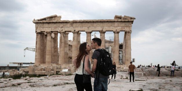 U.S. visitors Zach Branch,19, right, and Madison Franklin, 18, both from California, kiss in front of the Parthenon during their visit at the Acropolis hill in Athens, on Wednesday, April 15, 2015. Vacations in Europe have a new attraction: the euro's steep drop in value is making the continent cheaper for tourists from across the world, especially the United States and China. Branch said that as a U.S. citizen is much cheaper to travel to Europe now, than it was two years ago. (AP Photo/Yorgos Karahalis)