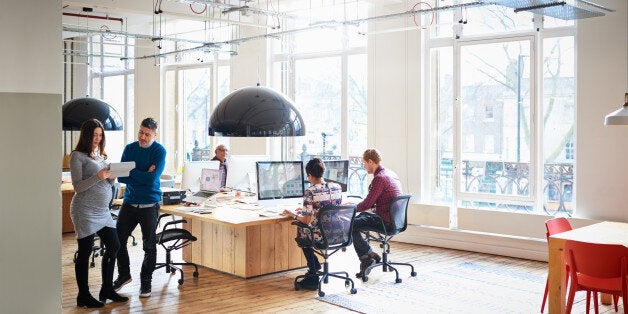 Businessmen and women working in a busy high-tech start-up office.