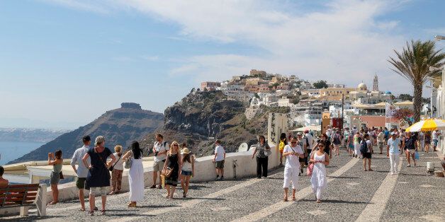 SANTORINI, GREECE - JUNE 30: Visitors walk around the typifies the white painted houses at Thera on June 30, 2015 in Santorini, Greece.The traditional architecture of Santorini with low-lying cubical houses, made of local stone and whitewashed or limewashed with various volcanic ashes used as colours. When strong earthquakes struck the island in 1956, half the buildings were completely destroyed.(Photo by Athanasios Gioumpasis/Getty Images)