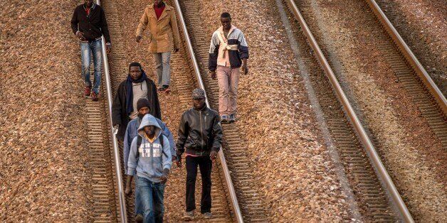 Migrants walk on railway tracks in Coquelles, near Calais northern France, headed toward the Eurotunnel terminal on August 12, 2015. Some 3,000 migrants and refugees, including many fleeing war and persecution in countries like Syria, Libya and Eritrea, are camped out in a makeshift tent village in Calais waiting for a chance to cross to Britain. AFP PHOTO / PHILIPPE HUGUEN (Photo credit should read PHILIPPE HUGUEN/AFP/Getty Images)