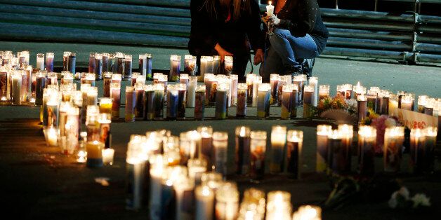 Meriah Calvert, left, of Roseburg, Ore., and an unidentified woman pray by candles spelling out the initials for Umpqua Community College after a candlelight vigil Thursday, Oct. 1, 2015, in Roseburg, Ore. A man opened fire at the school before dying in a shootout with police. (AP Photo/John Locher)