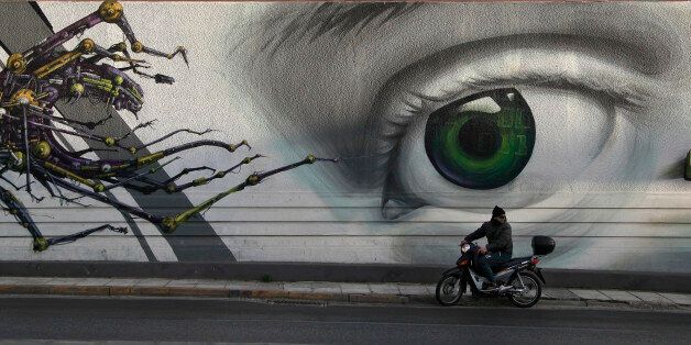 In this photo taken on Thursday Feb. 20, 2014, a motorcyclist passes the work 'Access Control' by Greek street artist iNO, on central Pireos Street in Athens. Greece has attracted international street artists to its capital, due to the availability of commissioned work and relatively lax anti-graffiti law. (AP Photo/Dimitri Messinis)