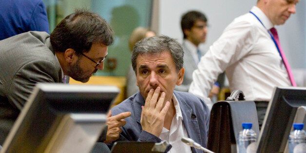 Greek Finance Minister Euclid Tsakalotos, center, speaks with a member of his delegation during a round table meeting of eurogroup finance ministers at the EU Lex building in Brussels on Sunday, July 12, 2015. Greece has another chance Sunday to convince skeptical European creditors that it can be trusted to enact wide-ranging economic reforms which would safeguard its future in the common euro currency. (AP Photo/Virginia Mayo)
