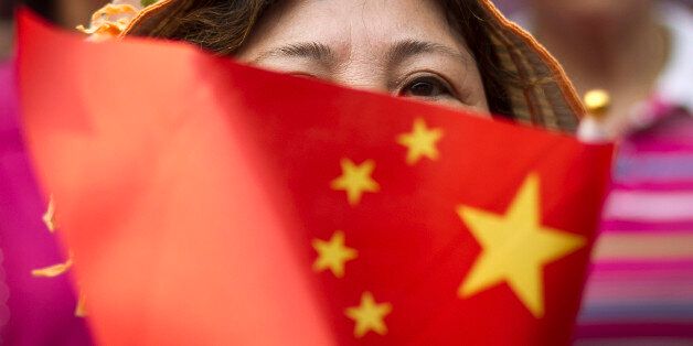 A Chinese woman holds a national flag as Chinese people gather at Jingshan Park to sing patriotic songs to celebrate the up-coming 90th anniversary of the founding of the Communist Party of China in Beijing, China Tuesday, June 14, 2011. China will celebrate the anniversary on July 1. (AP Photo/Andy Wong)