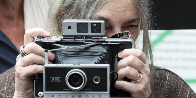 US singer-songwriter Patti Smith poses with her camera in front of a stretch of the Berlin wall on May 21, 2015. Smith and Dercon will present Amnesty International's Ambassador of Conscience Awards 2015 to US singer Joan Baez and Chinese artist Ai Wei-Wei during a ceremony on May 21, 2015 AFP PHOTO / JOHN MACDOUGALL (Photo credit should read JOHN MACDOUGALL/AFP/Getty Images)