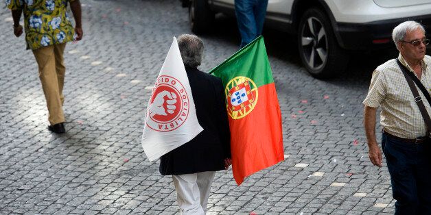 A supporter of Antonio Costa, leader of the Socialist party, holds flags during the final round of campaigning ahead of the Portuguese election in Lisbon, Portugal, on Friday, Oct. 2, 2015. In Portugal, there's a reluctance to rock the boat as voters cast their verdict on Prime Minister Pedro Passos Coelho's stewardship of a rescue program that is starting to pay off even if debt remains high. Photographer: Paulo Duarte/Bloomberg via Getty Images