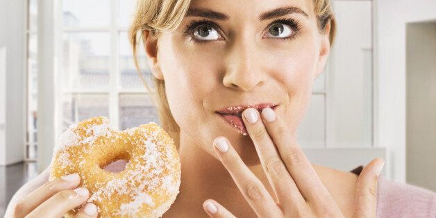 Blonde woman eating a sugar coated doughnut