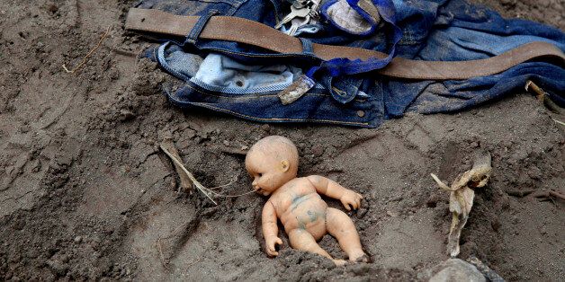 In this Saturday, Oct. 3, 2016 photo, a doll and clothing lay in the mud as rescue workers continue to search the site of a mudslide in Cambray, a neighborhood in the suburb of Santa Catarina Pinula, on the outskirts of Guatemala City. Rescue workers recovered more bodies Saturday after a hillside collapsed on homes late Thursday, while more are feared still buried in the rubble. (AP Photo/Luis Soto)