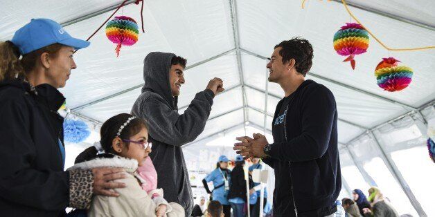 British actor and UNICEF Goodwill Ambassador Orlando Bloom (R) smiles as he speaks with a Syrian refugee from Damascus Tarek Merry during his visit at the refugee registration camp near Gevgelija on September 28, 2015. AFP PHOTO / ARMEND NIMANI (Photo credit should read ARMEND NIMANI/AFP/Getty Images)