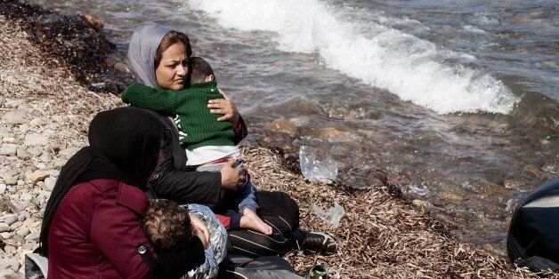 Refugee women sit with their children on Eftalou beach, west of the port of Mytilene, on the Greek island of Lesbos after crossing the Aegean sea from Turkey on September 21, 2015. Europe's migrant crisis took centre-stage at the UN human rights council, as European states said the need to end the conflict in Syria was at an all-time high. AFP PHOTO / IAKOVOS HATZISTAVROU (Photo credit should read IAKOVOS HATZISTAVROU/AFP/Getty Images)