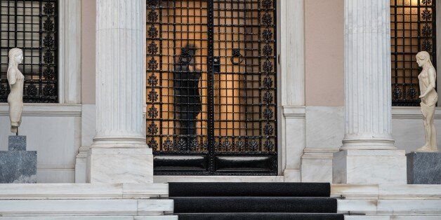 A person is seen through the glass door of the Maximou' palace which houses the offices of the Greek Prime Minister Alexis Tsipras, in Athens on July 14, 2015. Prime Minister Alexis Tsipras promised Greeks he would not abandon ship despite fractures within the government over draconian reforms eurozone creditors have demanded in exchange for a bailout. AFP PHOTO / ANDREAS SOLARO (Photo credit should read ANDREAS SOLARO/AFP/Getty Images)
