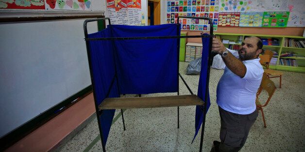 A municipal worker sets up a voting booth among other election materials at a school's classroom that will be a polling station for the Sept. 20 elections, in central Athens Friday, Sept. 18, 2015. It is the third time this year Greeks will be voting, with the economy still in dire straits, a quarter of workers jobless, and capital controls limiting cash access to savings to 420 euros ($470) per week. (AP Photo/Lefteris Pitarakis)